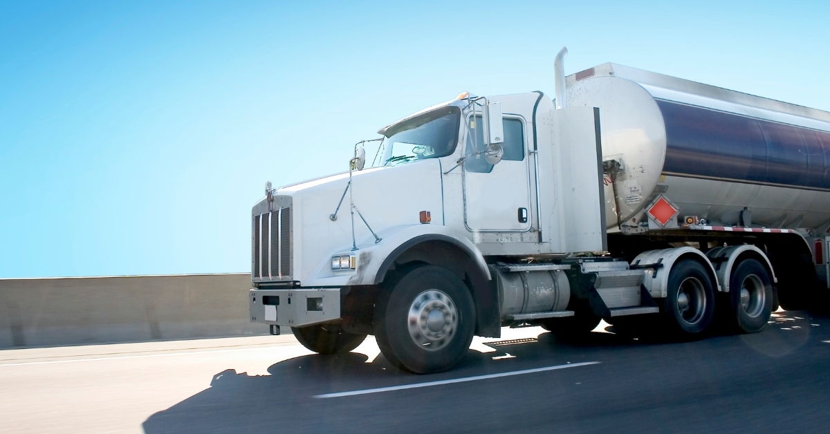 ISAAC Telematics Solutions for Tank Truck Fleet Management White tank truck equipped with ISAAC Instruments telematics solutions driving on a highway, symbolizing advanced fleet management for safety and efficiency.