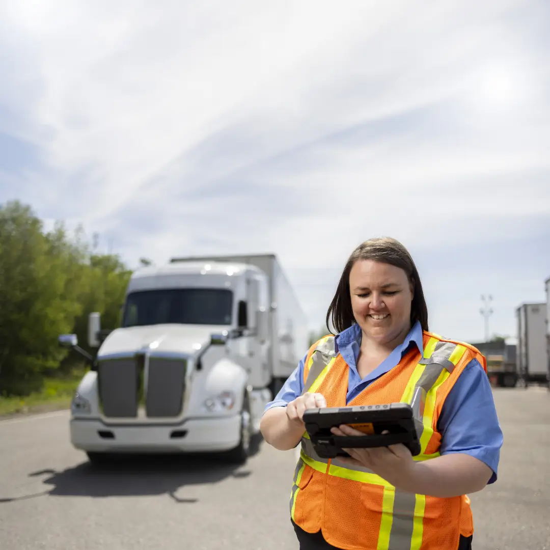 Fleet operator using the ISAAC platform tablet at a weigh station in front of a semi-truck.