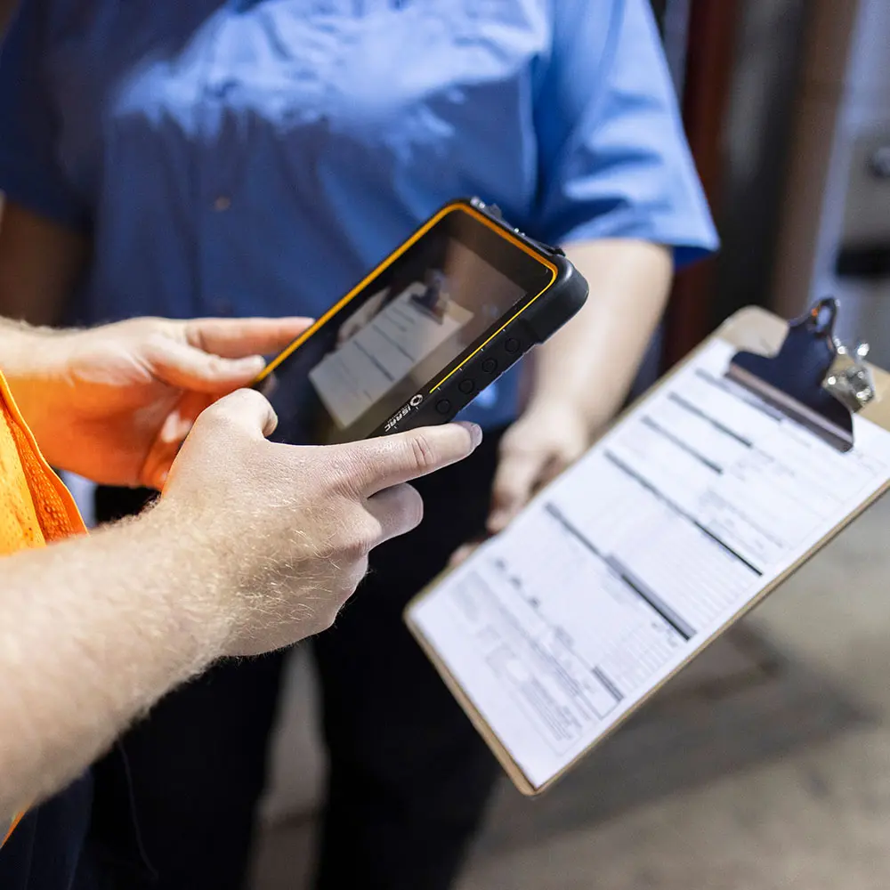 Fleet personnel using a rugged tablet to digitize documents beside a paper log clipboard