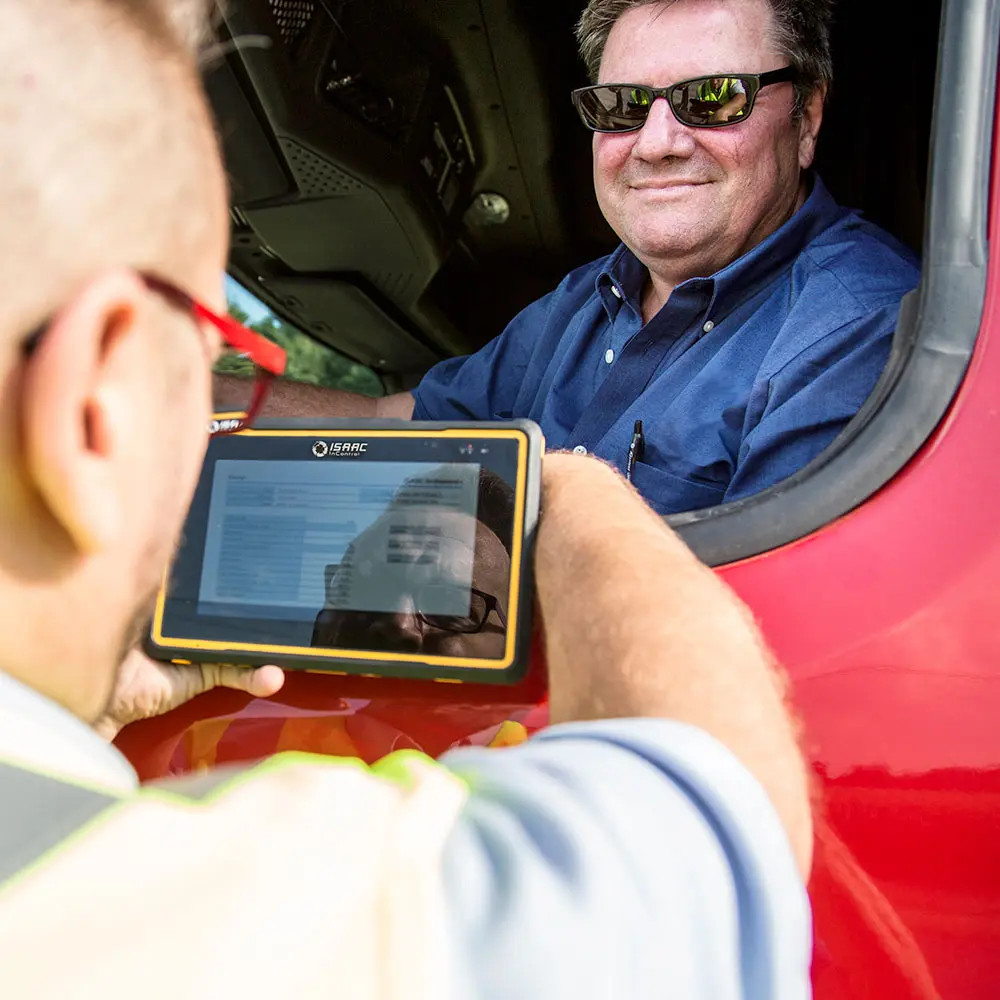 Truck driver accessing compliance tracking features on a mounted fleet tablet